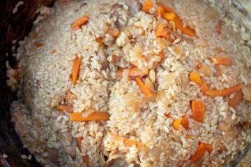 Cooking of Pilaf with beef, carrots, onions, garlic in a cauldron