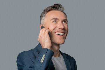Happy man with toothy smile communicating by smartphone