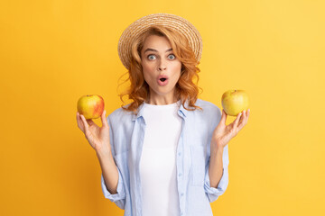 surprised young woman curly hair in summer straw hat with apple, healthy food