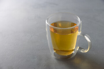 Glass mug of green herbal tea on grey background