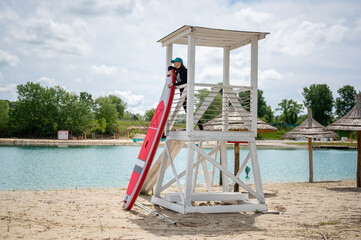 Woman standing at lifeguard tower at the beach with stand up paddle