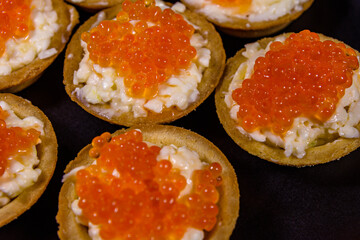Tartlets with red caviar on a black plate. Festive food