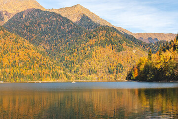 Beautiful view on the mountain lake with the colorful autumn trees on the hills.