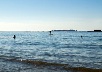  A man floats a board with a paddle in his hands along the beach in Saint Malo. Brittany, France