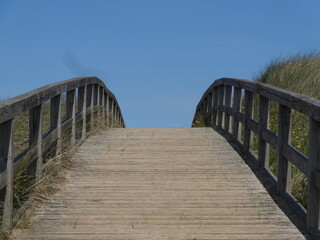 Holzbrücke auf dem Weg zum Meer mit blauem Himmel