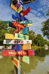 Signpost with signs indicating the direction of various cities in the world with different colors...