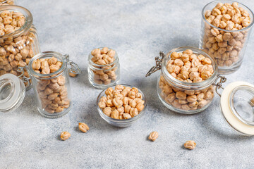 Uncooked dried chickpeas in different glass jars and bowls.