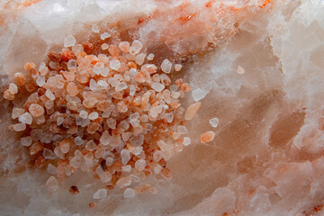 Heap of large crystals of pink Himalayan salt on the surface of a large slab of Himalayan salt