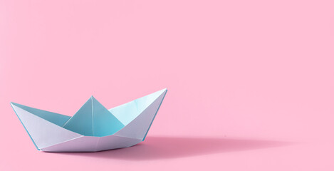 Folded paper origami blue ship with shadow  on pink background with copy space