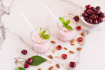 Fresh healthy cherry and almond smoothie on marble background. Decorated with mint leaves.