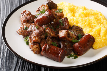 Romanian festive dish pomana porcului consisting of pieces of fried pork, sausages and offal served with corn porridge close-up on a plate on the table. Horizontal