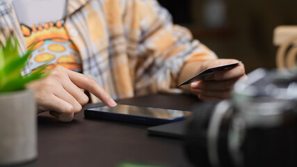 Cropped shot of freelance photographer using smartphone and holding credit card
