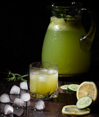 Glass of fresh cucumber lemonade on table with mint and ice