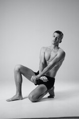 Obraz premium athlete sitting on the floor indoors in shorts and naked torso black and white photo of bodybuilder 