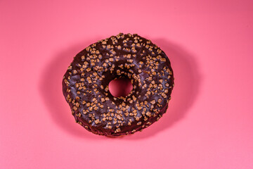 Donut with chocolate glaze on top isolated on a pink background
