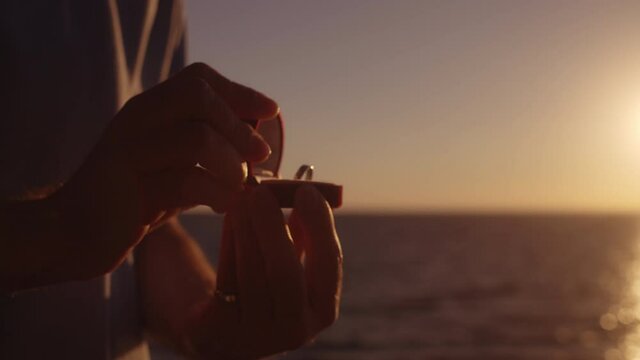 Close-up of male hands opening box with engagement ring, making proposal, love