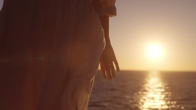 Feminine woman touching beautiful white gown, enjoying sea breeze at dawn