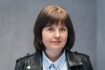 Portrait of young woman with bob haircut in leather jacket. Brunette girl with round face shape.