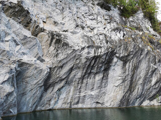 View from the water of the marble, sometimes overgrown with moss in the Marble Canyon in the mountain park Ruskeala on a sunny summer day