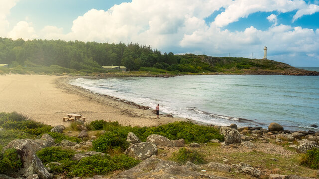 Lone traveller at varberg sweden beach staring at lighhouse hoping for light