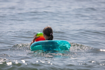 Little girl with a rubber ring. Children's safety on the water. Summer vacation at the sea. Beach...