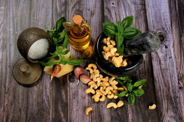 Pesto Ingredients: Fresh Basil, Garlic, Cashew Nuts, Olive Oil and Cheese, copy space, Ingredients for making pesto sauce on a dark wooden background, top view. pesto with Cashew 