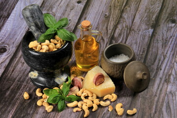 Pesto Ingredients: Fresh Basil, Garlic, Cashew Nuts, Olive Oil and Cheese, copy space, Ingredients for making pesto sauce on a dark wooden background, top view. pesto with Cashew 