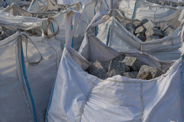 Cobblestones in a big bag on a construction site. - obrazy, fototapety, plakaty