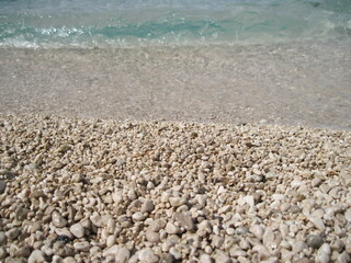 Wet pebbles on the beach on a sunny summer day. Calm waves on the beach.