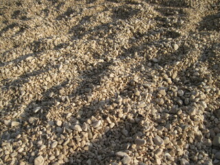 Macro view of gravel beach on the sun. Pebbles on the seaside. Close up of a stone on a sunny summer day.