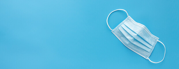 top view of a medical face mask on blue background. banner