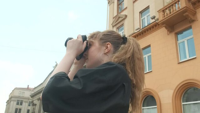 A young girl photographer walks around the city and takes photos on a retro camera. High quality 4k footage