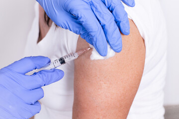 Female doctor or nurse giving shot or vaccine to patient's shoulder. Close-up. Vaccination against...
