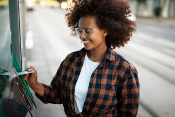 Beautiful African girl using ATM machine. Happy smiling young woman withdrawing money from credit...