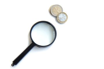 Magnifier and stack of coins isolated on white background. Concept of keeping money, investing. Flat lay