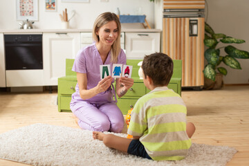 The therapist plays an educational game with the child using logic cards.