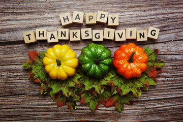 Happy Thanksgiving alphabet letter with pumpkins and autumn leaves on wooden background