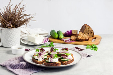 Canapes with toasted bread with sunflower and flax seeds, feta cheese, cucumber and onion