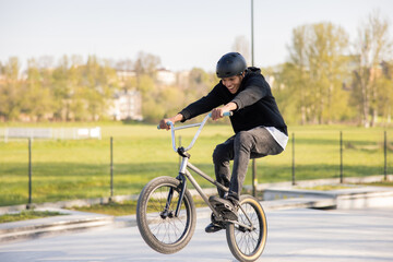A boy mastered riding a low trick bike,bmx, I try to lift the front wheel, he is fascinated,...