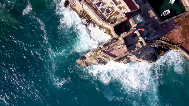 The waves crash against the rock on which the fortress stands. The quadcopter spirals to the right over the citadel of Montenegro, Petrovac.