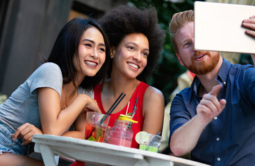 Multiracial group of friends having fun and talking in restaurant
