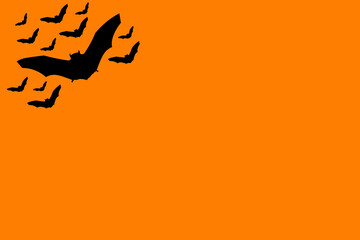 Several black bats flying over a orange background