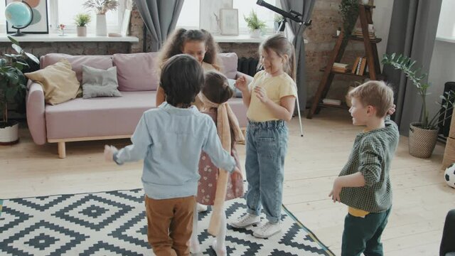 Handheld slowmo shot of cute little girl in blindfold playing catching and guessing game with her friends at home