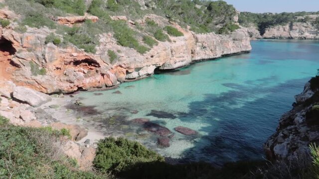 A clean beautiful beach in the Cala Millor, Spain surrounded by rocks