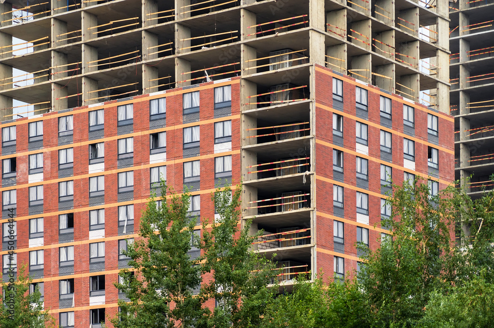Poster monolithic concrete frame of apartment building under construction with partially attached ready-mad