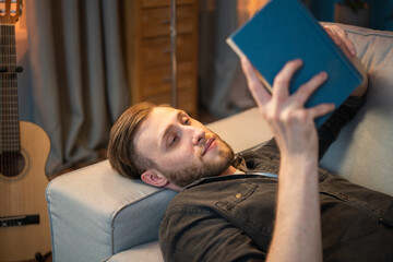 A dreamy young man with the soul of an artist is immersed in reading a love novel. He is lying on...