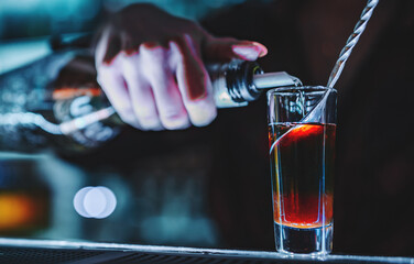 bartender hand making shot cocktail at the bar