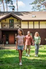 Happy kid walking on lawn near blurred family