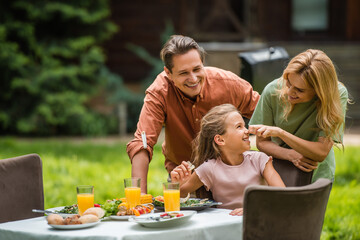 Cheerful family near tasty food during picnic outdoors