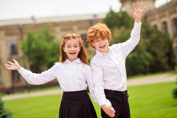 Photo of two funny pupil ginger schoolkids family hold hands have fun wear white shirt uniform park...